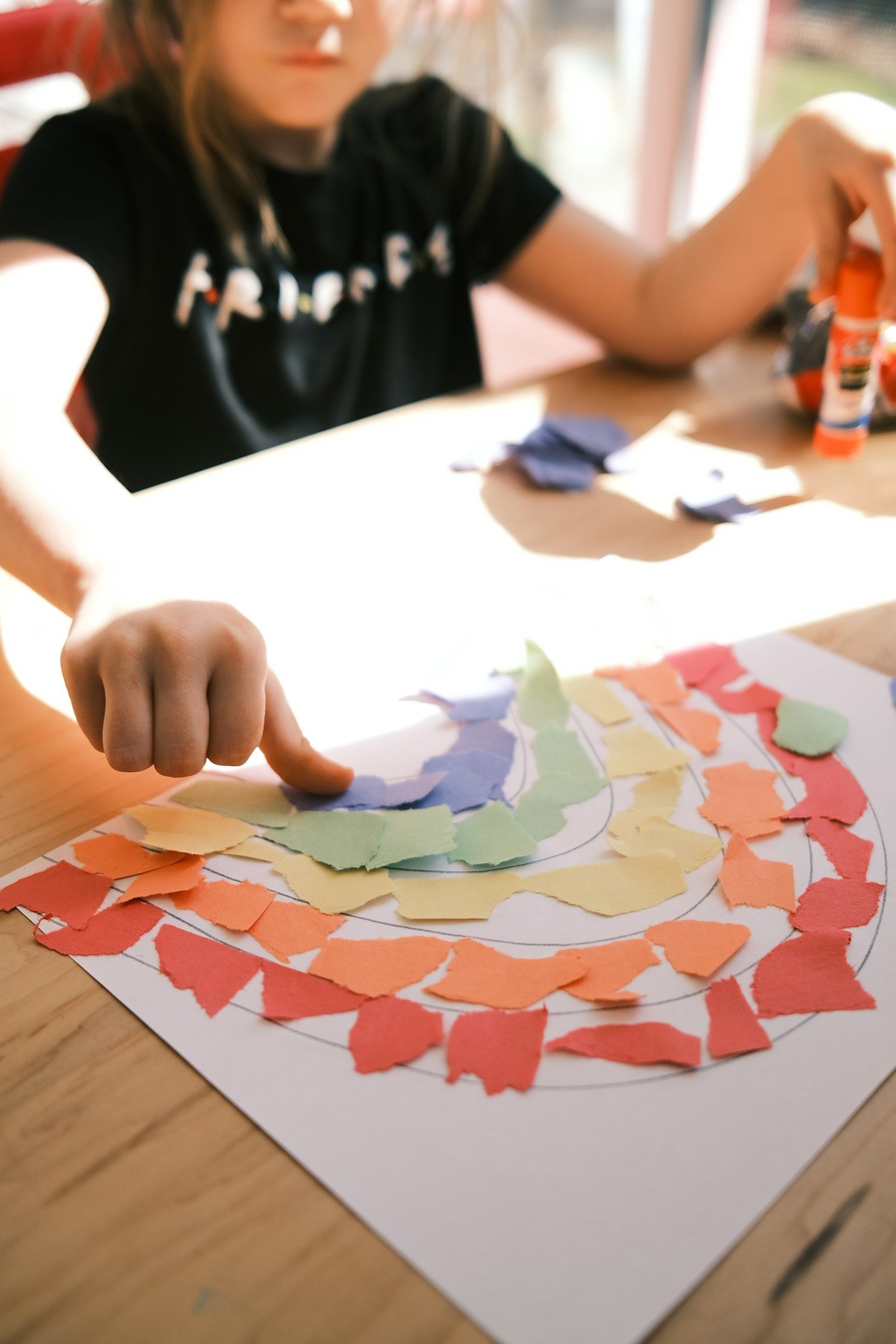 Child doing a colorful art collage during Craft Corner class
