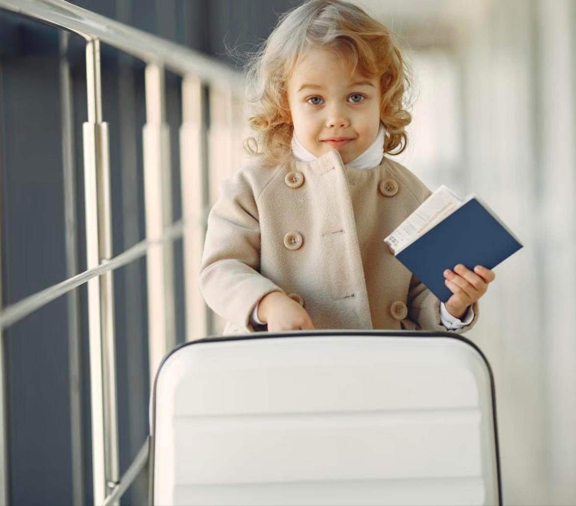 Child holding a passport and pulling a suitcase, ready for Passport Place class